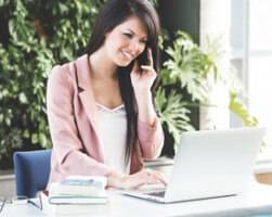 photo of woman on phone working at laptop