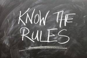 chalkboard writing of "know the rules" to illustrate business compliance regulations