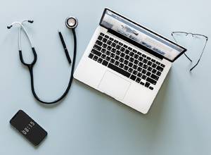 stethoscope laptop and phone to illustrate the risk to health care organizations from phishing emails