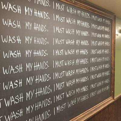 chalkboard with "I must wash my hands" written on it over and over.