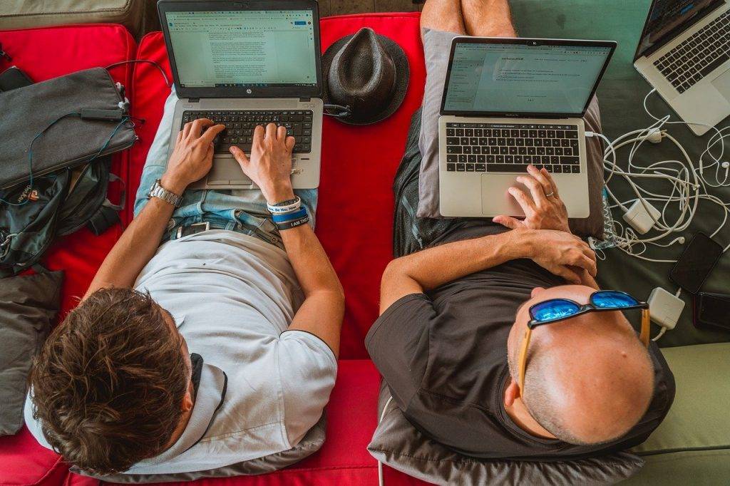 father and son on sofa with laptops