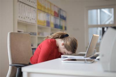 Illustrative photo of frustrated woman in red sweater with her head on her laptop 