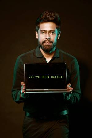 a frustrated-looking man holds a laptop with the words "you've been hacked" on the screen