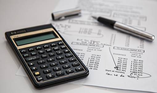 Photo of black calculator on top of sheet of paper with budget calculations and the note "Can we do this?" hand written on it.