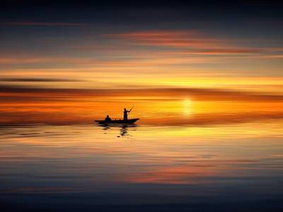 Image of sunset on the water, with a small boat silhouetted in the middle foreground. To illustrate the retirement of Skype for Business Online.