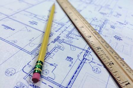 Photograph of pencil and ruler laying on top of a construction blueprint to illustrate how the NIST Cybersecurity Framework provides a guideline to protect your business.