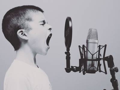 black & white image of boy with cropped hair yelling into microphone